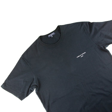 The flat lay of the Comme Des Garçons Homme Black T Shirt.