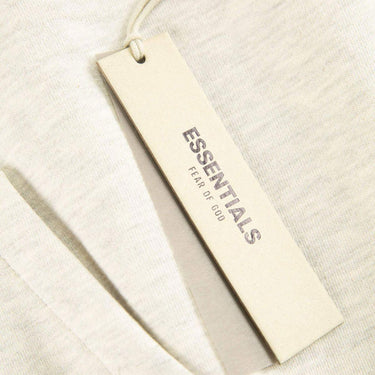 The tags of the Fear Of God ESSENTIALS Light Oatmeal Hoodie M.