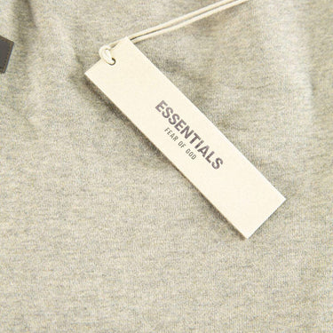 The tags of the Fear Of God ESSENTIALS Dark Oatmeal Shorts M.