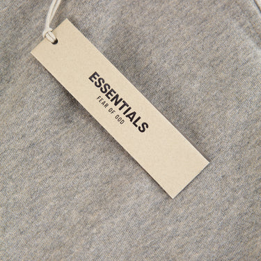 The tags of the Fear Of God ESSENTIALS Dark Oatmeal Sweatpants.