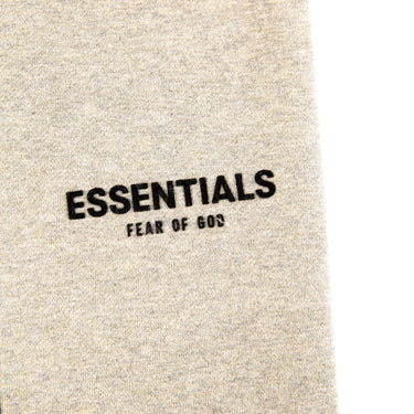 The front logo of the Fear Of God ESSENTIALS Light Oatmeal Sweatpants.