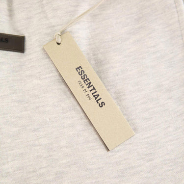 The tags of the Fear Of God ESSENTIALS Light Oatmeal Sweatpants L.