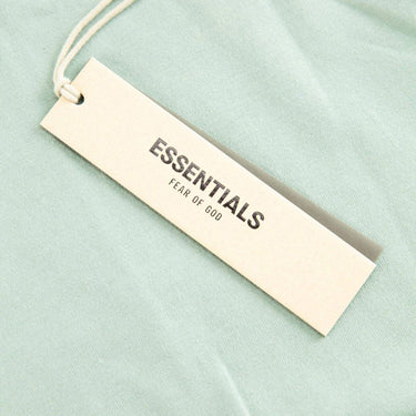 The tags of the Fear Of God ESSENTIALS Sycamore T Shirt XS.