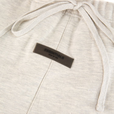 The front label of the Fear Of God ESSENTIALS Light Oatmeal Sweatpants.