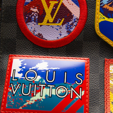 The logo of the Louis Vuitton District Messenger Damier Graphite Alps PM.