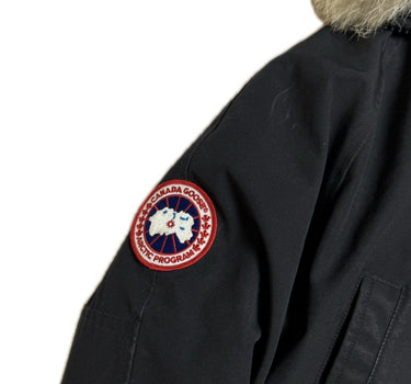 The arm logo of the Canada Goose Chilliwack Womens Black Bomber Heritage.