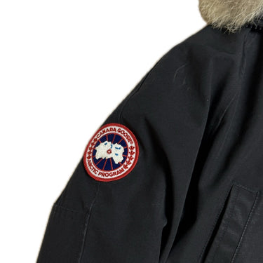 The arm logo of the Canada Goose Chilliwack Womens Black Bomber Heritage.