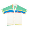 The front of a Casablanca Multicolor Crochet Tennis Shirt in white with blue, green, yellow, and red stripes.