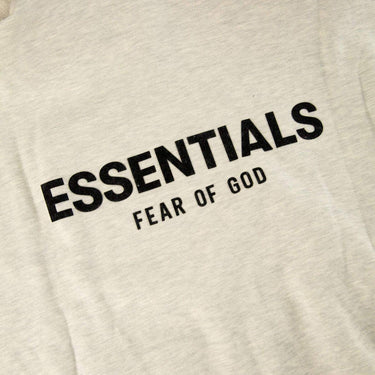 The logo of the Fear Of God ESSENTIALS Light Oatmeal Hoodie M.