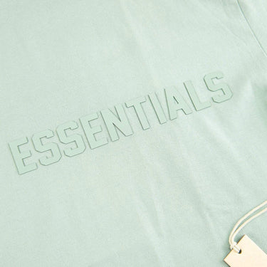 The logo of the Fear Of God ESSENTIALS Sycamore T Shirt L.
